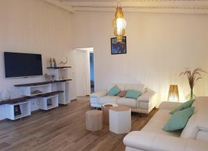 ein Wohnzimmer mit weißen Möbeln und einem Flachbild-TV in der Unterkunft La villa d'Emma in Sainte-Anne