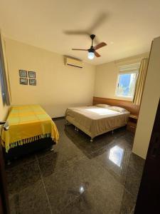 een slaapkamer met 2 bedden en een plafondventilator bij Condomínio Arituba Tropical in Nísia Floresta
