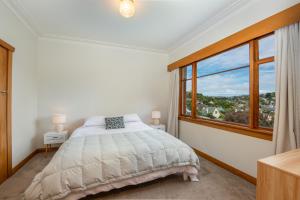 a bedroom with a bed and a large window at Stunning Family Home in Andersons Bay in Dunedin