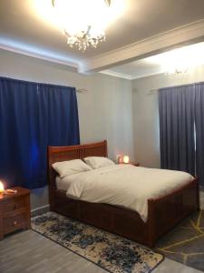 a bedroom with a large bed with blue curtains at Marie & Sons Property in Freetown