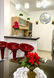 a kitchen with red stools and a table with flowers at Cusco Magico 9 - Loft Santa Ursula in Cusco