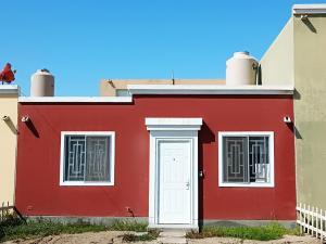 ein rotes Haus mit einer weißen Tür und Fenstern in der Unterkunft CASA CON COCHERA CERCA A LA PLAYA PlMENTEL in Chiclayo