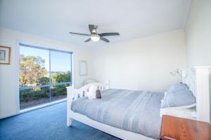 a white bedroom with a bed and a window at Banksia Waters in Lakes Entrance