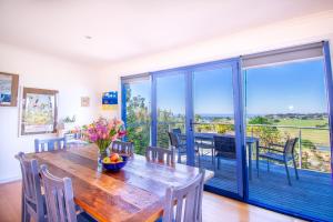 a dining room with a wooden table and a balcony at Banksia Waters in Lakes Entrance
