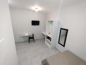 Habitación blanca con escritorio y espejo. en Xavi Studio - Proximo ao Boulevard Shopping, Av Nacoes Unidas e Nuno de Assis. en Bauru
