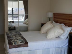 a bedroom with a large white bed with a mirror at Windsurfer Resort in Gold Coast