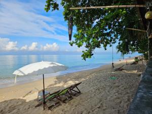 a beach with chairs and an umbrella and the ocean at Lanta Riviera Resort - SHA Extra Plus in Ko Lanta