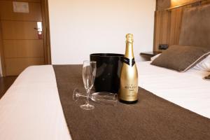 a bottle of champagne and a wine glass on a bed at Gce Hoteles in Málaga