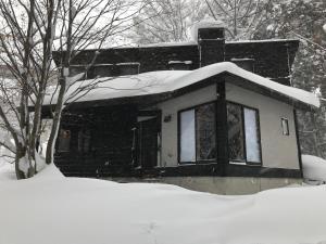 ein schneebedecktes Haus mit einem Schneehaufen in der Unterkunft Sunnsnow Kallin Cottage in Nagano
