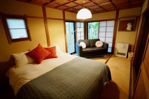 ein Schlafzimmer mit einem Bett, einem Sofa und Fenstern in der Unterkunft Sunnsnow Kallin Cottage in Nagano