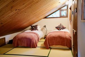2 Betten in einem kleinen Zimmer mit Fenster in der Unterkunft Sunnsnow Kallin Cottage in Nagano