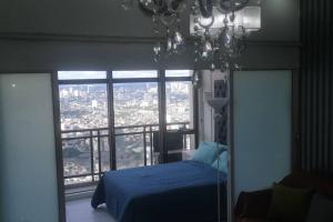 a bedroom with a blue bed and a large window at Penthouse at Poblacion - 200Mbs net - Awesome view in Manila