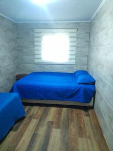 een slaapkamer met een blauw bed en een raam bij Cabaña en Ritoque in Quintero