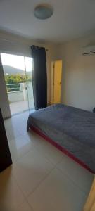 1 dormitorio con cama y ventana grande en Residencial Ilha Bela, en Bombinhas