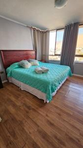 a bedroom with a bed with a green comforter at Departamento en Playa Brava Iquique 1 dormitorio 1 baño in Iquique