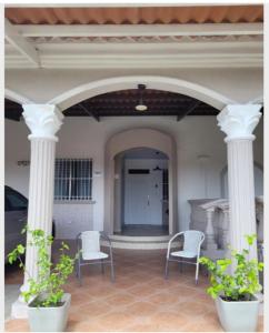 un porche con 2 sillas y 2 columnas en Acogedor apartamento en San Miguelito