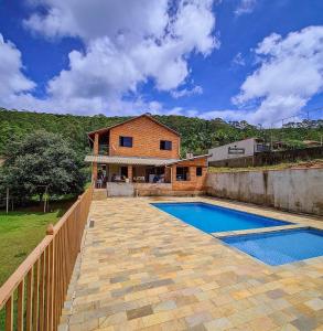 uma casa com uma piscina ao lado de uma cerca em Chácara monte tabor em Poços de Caldas