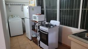 y cocina con fogones, microondas y nevera. en Acogedor apartamento en San Miguelito