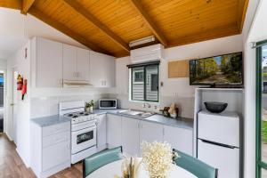 a kitchen with white cabinets and a wooden ceiling at Tasman Holiday Parks - Geelong in Geelong