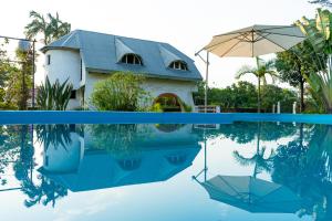 een huis en een parasol worden weerspiegeld in een zwembad bij " Casa quinta "San Bernardo" Con Pileta y amplio jardín in Posadas
