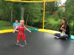 a woman and two children playing on a trampoline at Camping La Clé des Champs in Saint-Nectaire