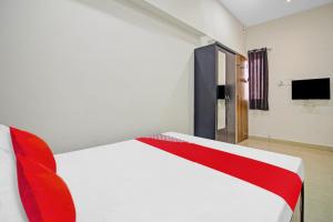 Schlafzimmer mit einem roten und weißen Bett und einem TV in der Unterkunft Flagship Crossroad Rooms in Nagpur