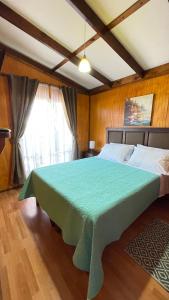 a bedroom with a large bed with a green blanket at CABAÑA VIP in Caldera