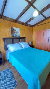 1 dormitorio con 1 cama grande y edredón azul en CABAÑA VIP, en Caldera