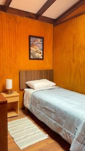1 dormitorio con 1 cama y 1 mesa con lámpara en CABAÑA VIP, en Caldera