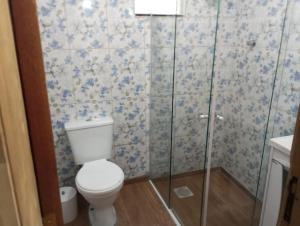 a bathroom with a toilet and a glass shower at Casas de Aluguel da Lulu in Itapema