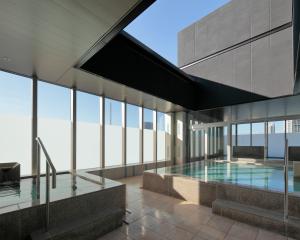 a swimming pool in a building with glass windows at Candeo Hotels Osaka Shinsaibashi in Osaka