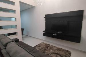 a living room with a couch and a flat screen tv at Casa TOP 1 Suite e 2 Quartos todos com Ar Condicionado in Guanambi