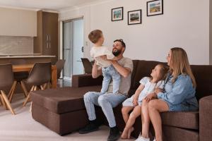 una familia sentada en un sofá en una sala de estar en Rydges Resort Hunter Valley en Lovedale