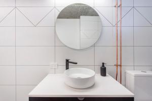 een witte badkamer met een wastafel en een spiegel bij Studio Escape in Hamilton Hill