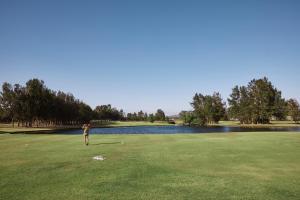 Um homem está a jogar golfe num campo de golfe. em Rydges Resort Hunter Valley em Lovedale
