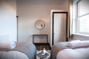 a white bedroom with two beds and a mirror at The Port Solent City Apartment - Southampton, Portsmouth in Southampton