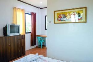 una camera con un letto e una TV su un comò di Mommy Linda Beach Resort a Cabangan