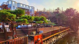 a bridge over a river with a building and trees at Travely Hotel Gapyeong in Gapyeong