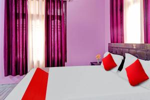 a bedroom with a large bed with red pillows at Flagship Hotel The Pinkcity in Patna