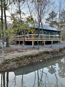 a house sitting on a dock next to a body of water at Livin on the Edge Cabin in Albert Pike, Brand New! in Caddo Gap