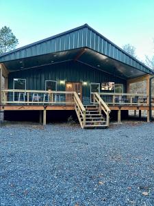 a large green barn with wooden stairs in front of it at Livin on the Edge Cabin in Albert Pike, Brand New! in Caddo Gap