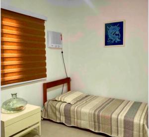 1 dormitorio con cama, mesa y ventana en Casinha da Rena em Cambury en São Sebastião