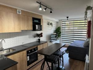 a kitchen and living room with a table and a couch at Departamento Royal Suite 2 Chillan - Centro - Factura - Empresa - Parking - wifi in Chillán