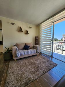 a couch in a living room with a large window at Departamento grande cercano a la playa La Serena in La Serena