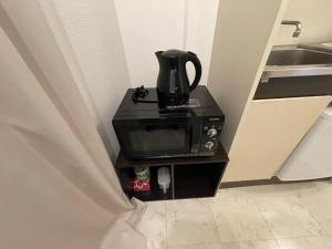 a coffee pot sitting on top of a microwave at A&C STAY Shin-Osaka83 in Osaka