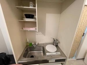 a small kitchen with a sink and shelves at A&C STAY Shin-Osaka83 in Osaka