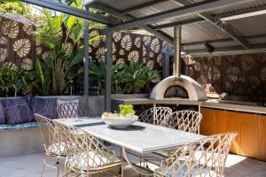a table and chairs on a patio with an outdoor oven at Resort Style home close to the Beach with Pool, Sauna and Pizza Oven in Sydney