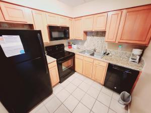 a kitchen with wooden cabinets and a black refrigerator at F3 close to front heated pool in Mallory Park