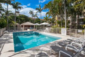 - une piscine avec des chaises longues et des palmiers dans l'établissement Santa Monica Apartments - Hosted by Burleigh Letting, à Gold Coast