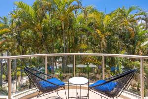 dwa krzesła i stół na balkonie z palmami w obiekcie Santa Monica Apartments - Hosted by Burleigh Letting w mieście Gold Coast